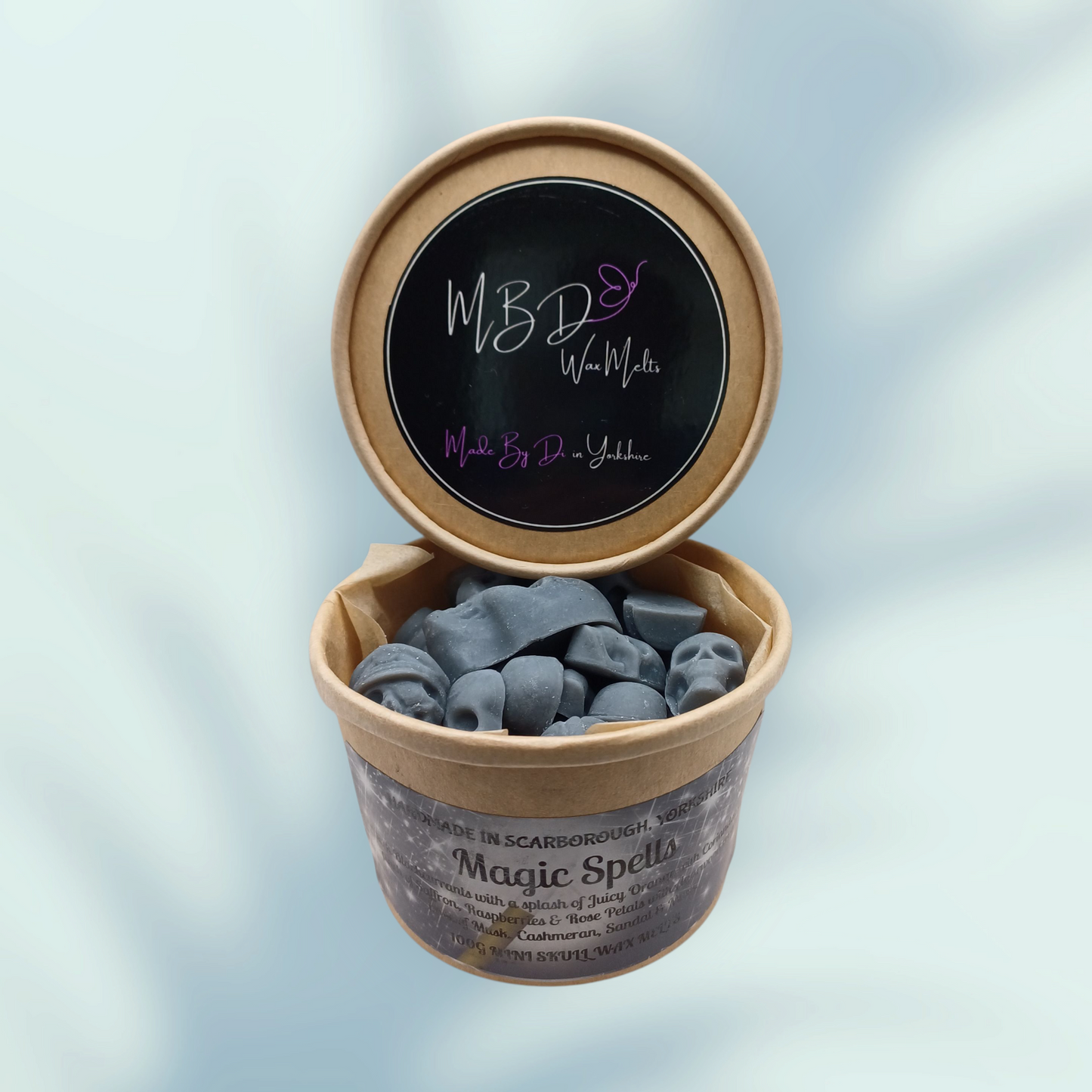 Open container of mini skull wax melts on a blue background.