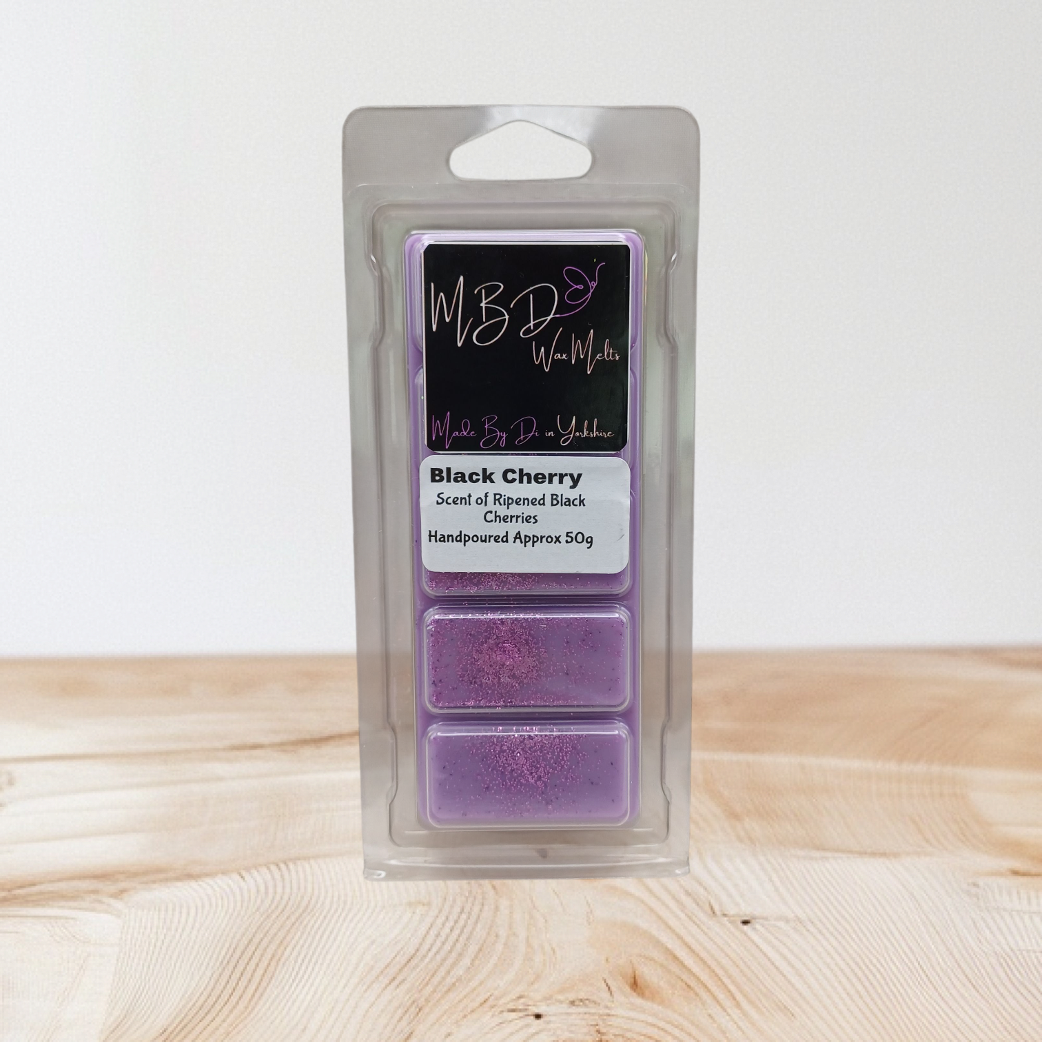 Packaged wax melts with 'Black Cherry' scent on a wooden surface