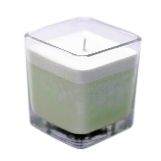 Square glass candle with a white candle inside on a white background