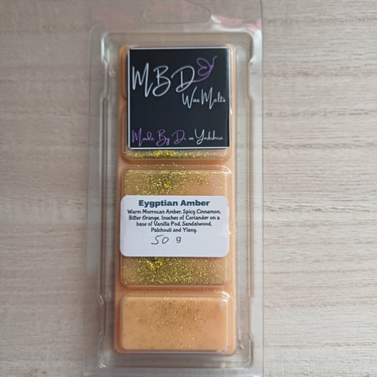 Packaged Egyptian Amber wax melts with a label on a wooden surface