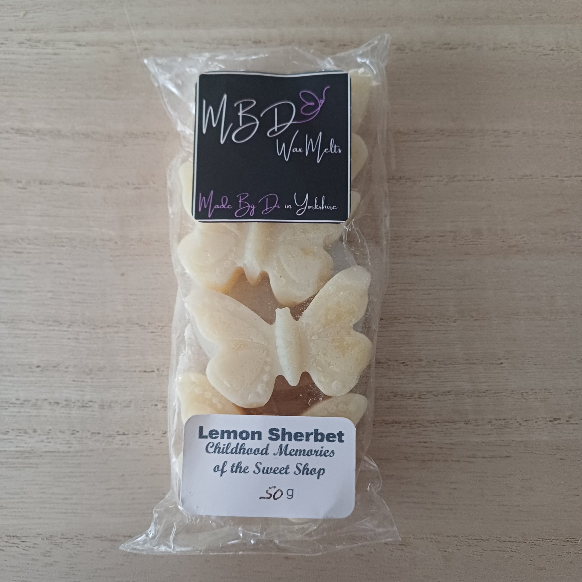 Packaged Lemon Sherbet Butterfly Shaped Wax Melts on aWooden background