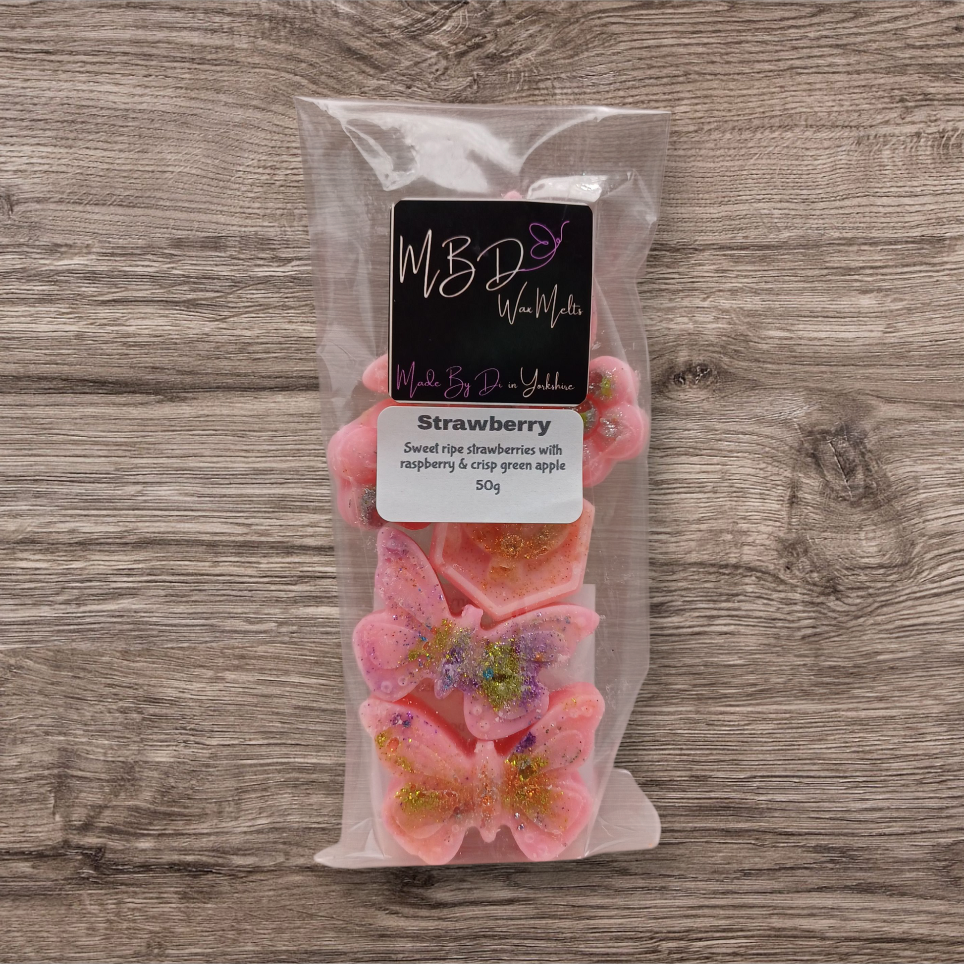 Packaged strawberry wax melts with a label on a wooden surface