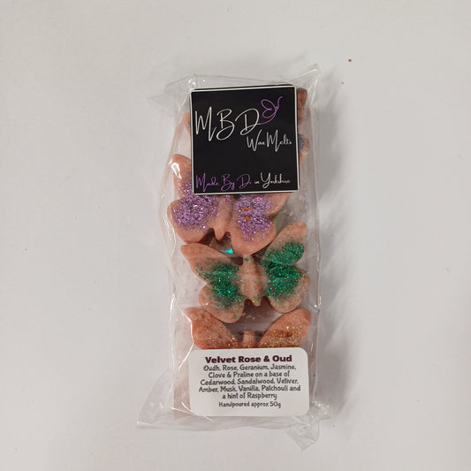 Packaged butterfly-shaped wax melts with colourful glitter on a white background