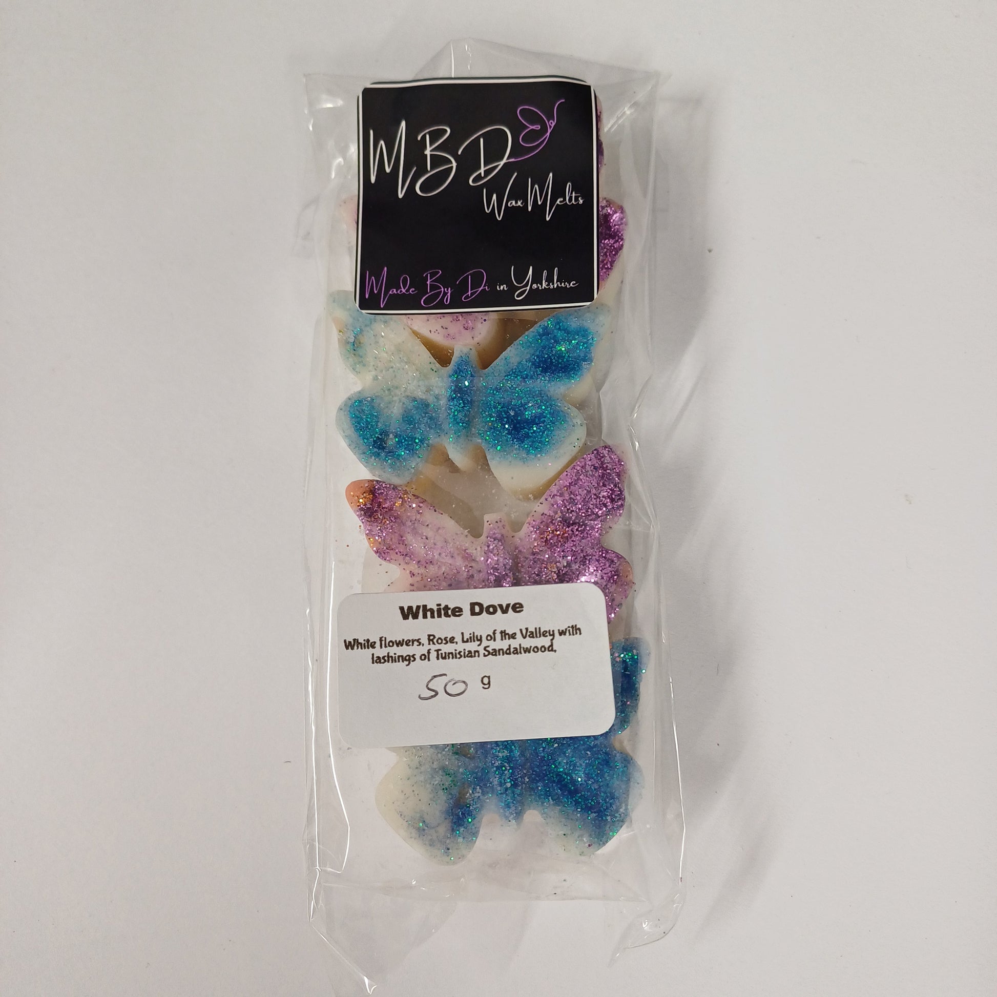 Packaged butterfly-shaped wax melts with colourful glitter on a white background